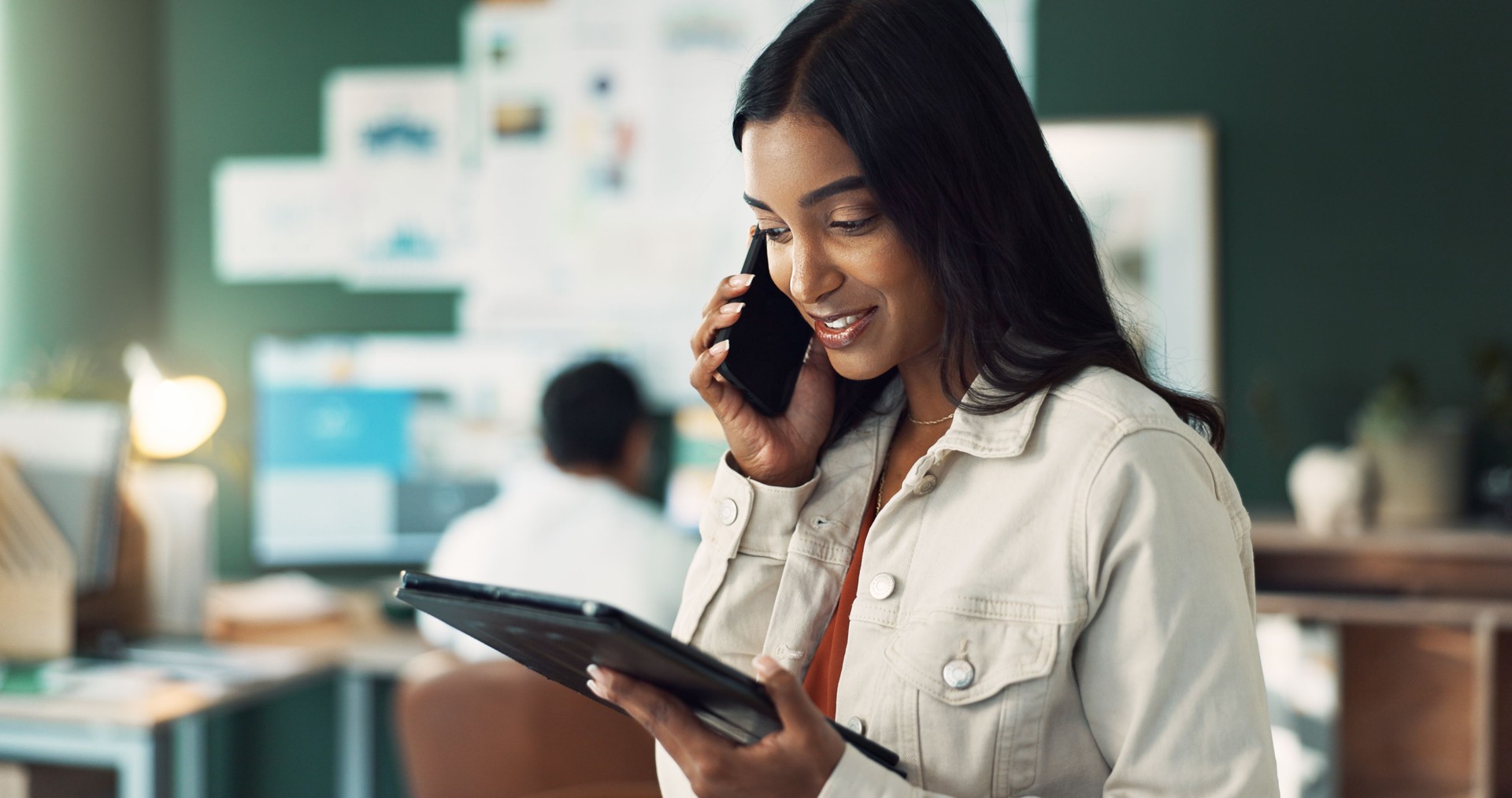 Business woman on tablet and conversation on phone call in office for manage schedule, appointment and meetings for client. Female employee, technology and professional engagement for feedback, online and work. A sales call.